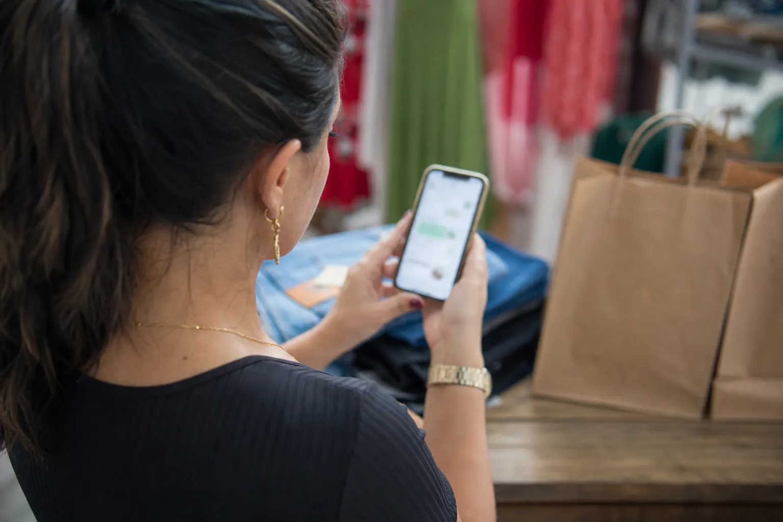 Vendedora de loja de roupas lendo a conversa do cliente no celular antes de assumir o atendimento